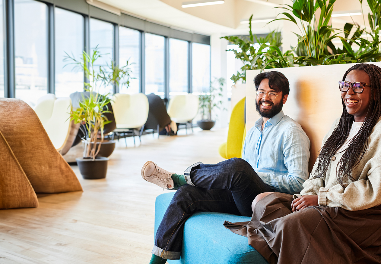 Two Deliveroo employees sitting down smiling