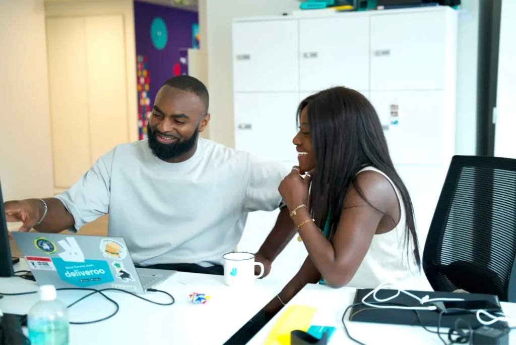 Two Deliveroo employees working at a laptop